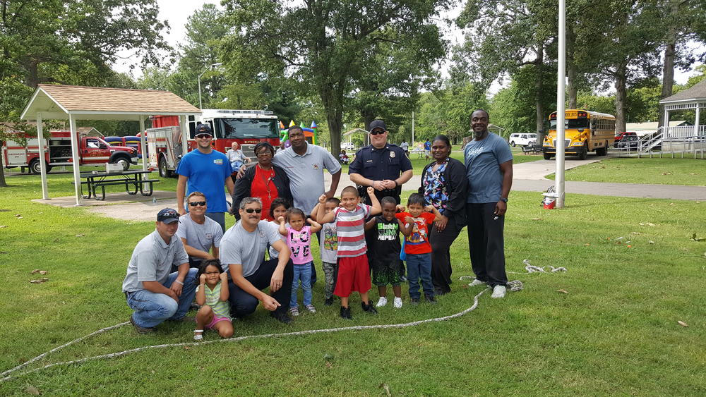 A group of adults and children standing with law enforcement officers at a park