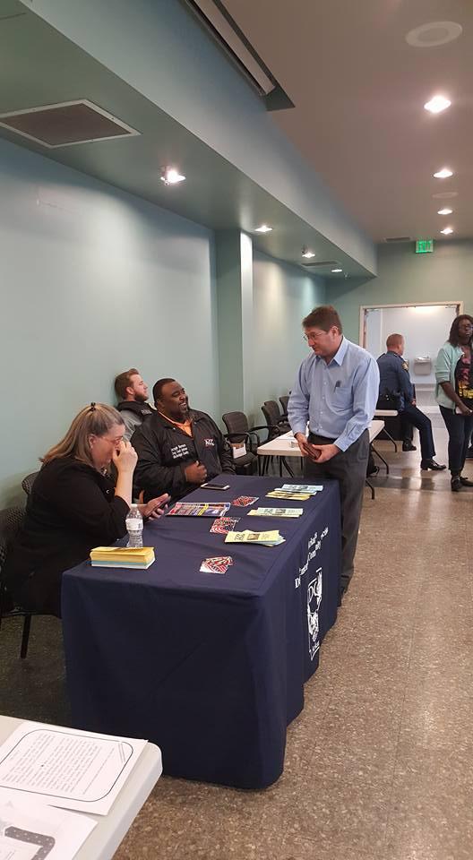 Intake Officer Daryl Turner of the Juvenile Probation Office speaking to three adults at a table