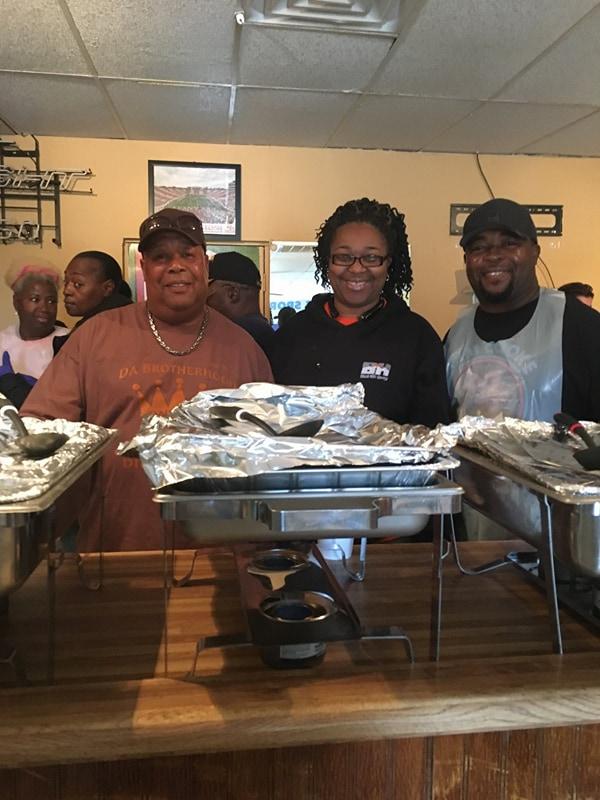 Three people smiling for the camera and getting food