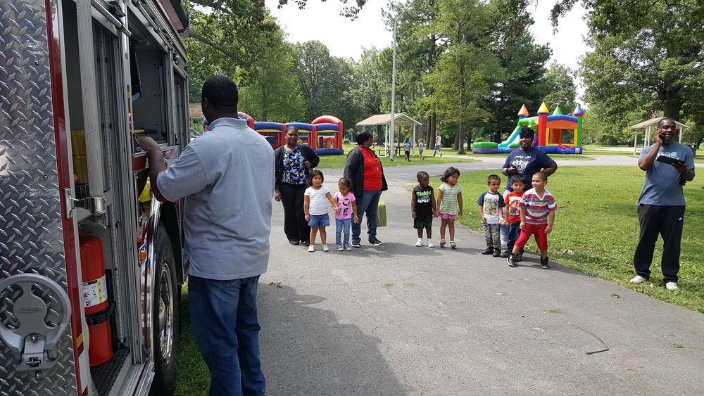 A man showing adults and children a firetruck at a park