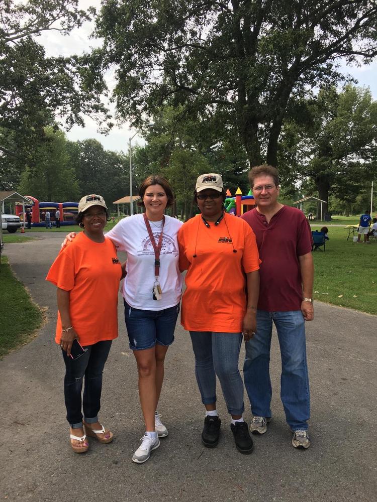 Four adults standing together and smiling for the camera