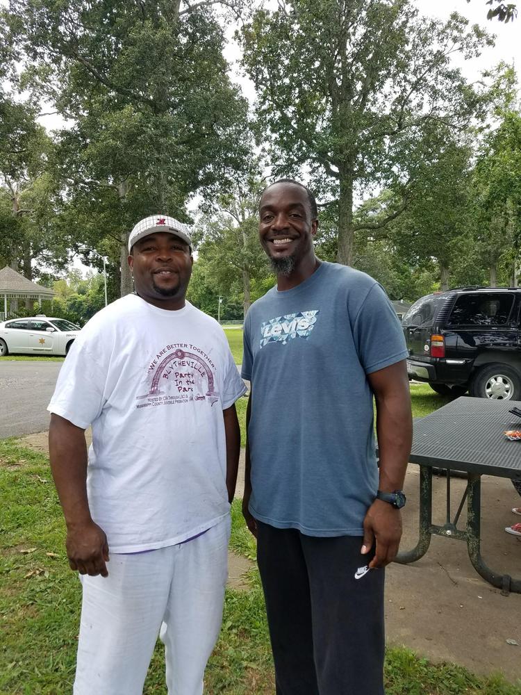 Two men smiling for the camera at a park